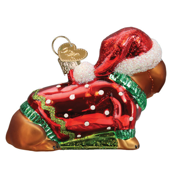 Glass dachshund puppy ornament wearing a red Santa hat and a red polka dot sweater with green trim.