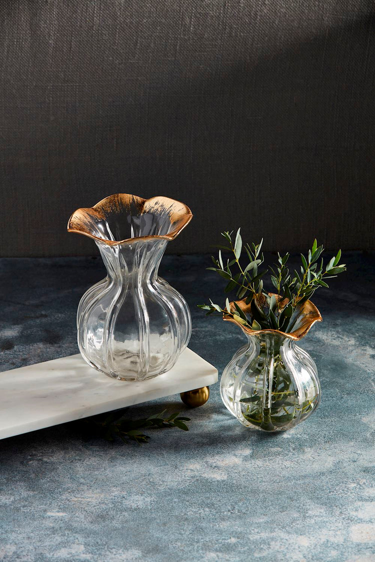 Two clear glass vases with fluted bodies and hand-painted gold ruffle rims on a marble tray.