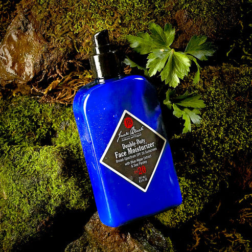 8.5oz Jack Black Double-Duty Face Moisturizer SPF 20 bottle on a mossy rock background.