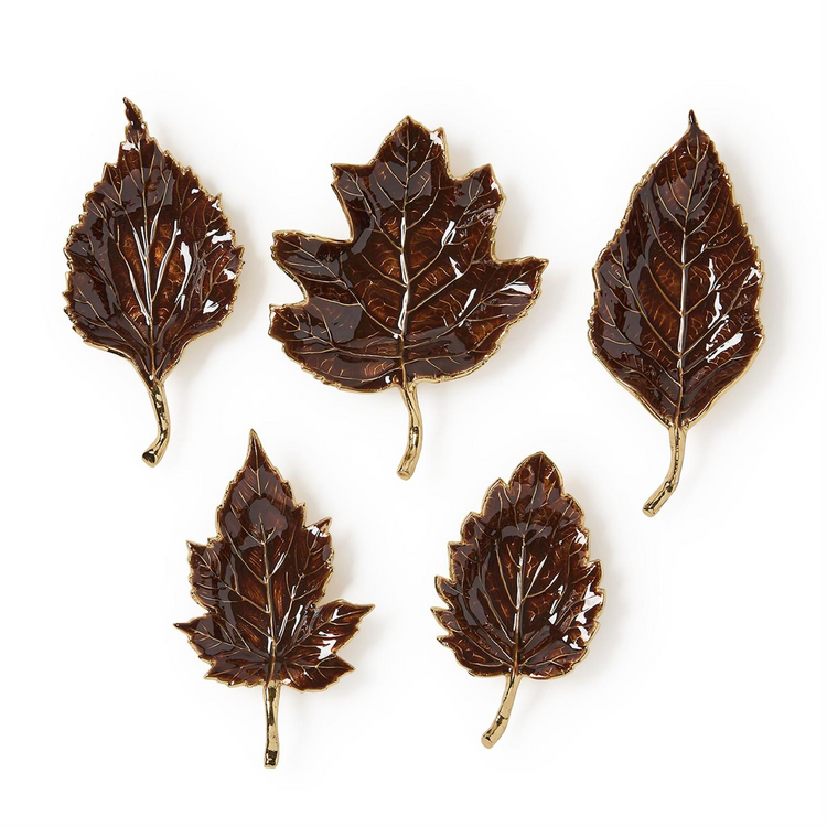 Set of five brown enameled leaf trays with gold-toned stems and edges in various leaf shapes.