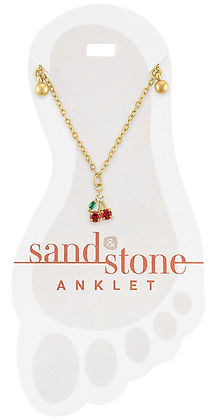 Gold chain anklet with a cherry charm featuring red and green stones on a foot-shaped card.