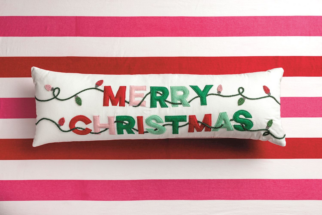 White lumbar pillow with embroidered 'Merry Christmas' text and festive light string detail.
