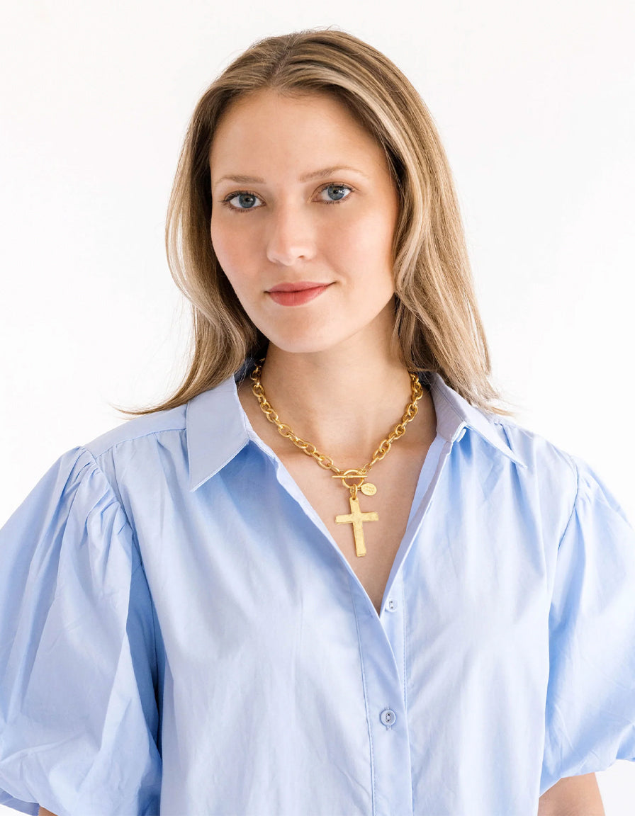 Woman wearing a gold Classic Cross Toggle Necklace with a chunky chain and large cross pendant.