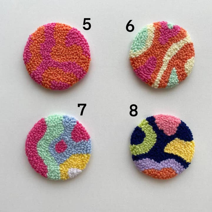 Four colorful, round punch needle car coasters with wavy patterns, numbered 5 through 8.