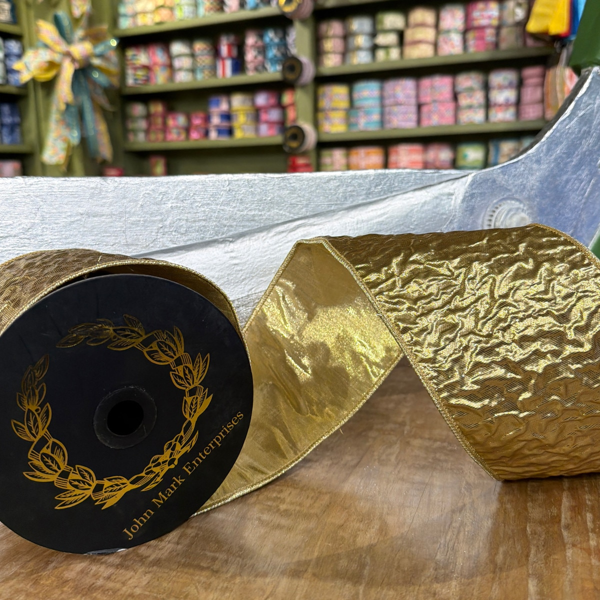 4 inch wide gold crinkle metallic dupion fused ribbon on a black spool.
