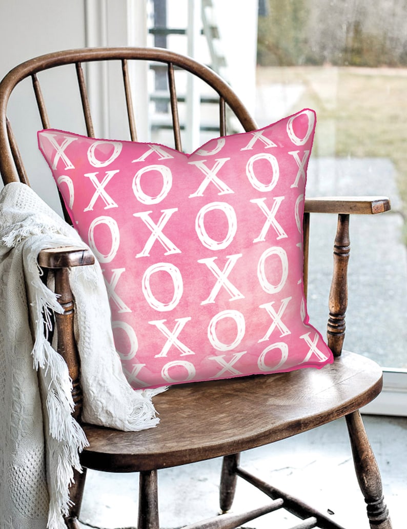 Pink decorative pillow featuring a watercolor XOXO art pattern by Rachel Brooks Design.