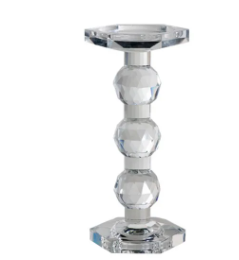 Tall solid glass pillar candle holder with geometric cut shapes creating a prismatic visual effect.