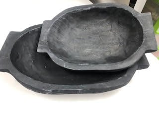 Two black paulownia wood oval dough bowls in small and large sizes.