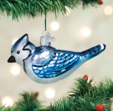 Bright blue jay ornament with detailed crest feathers on a natural wood stand.