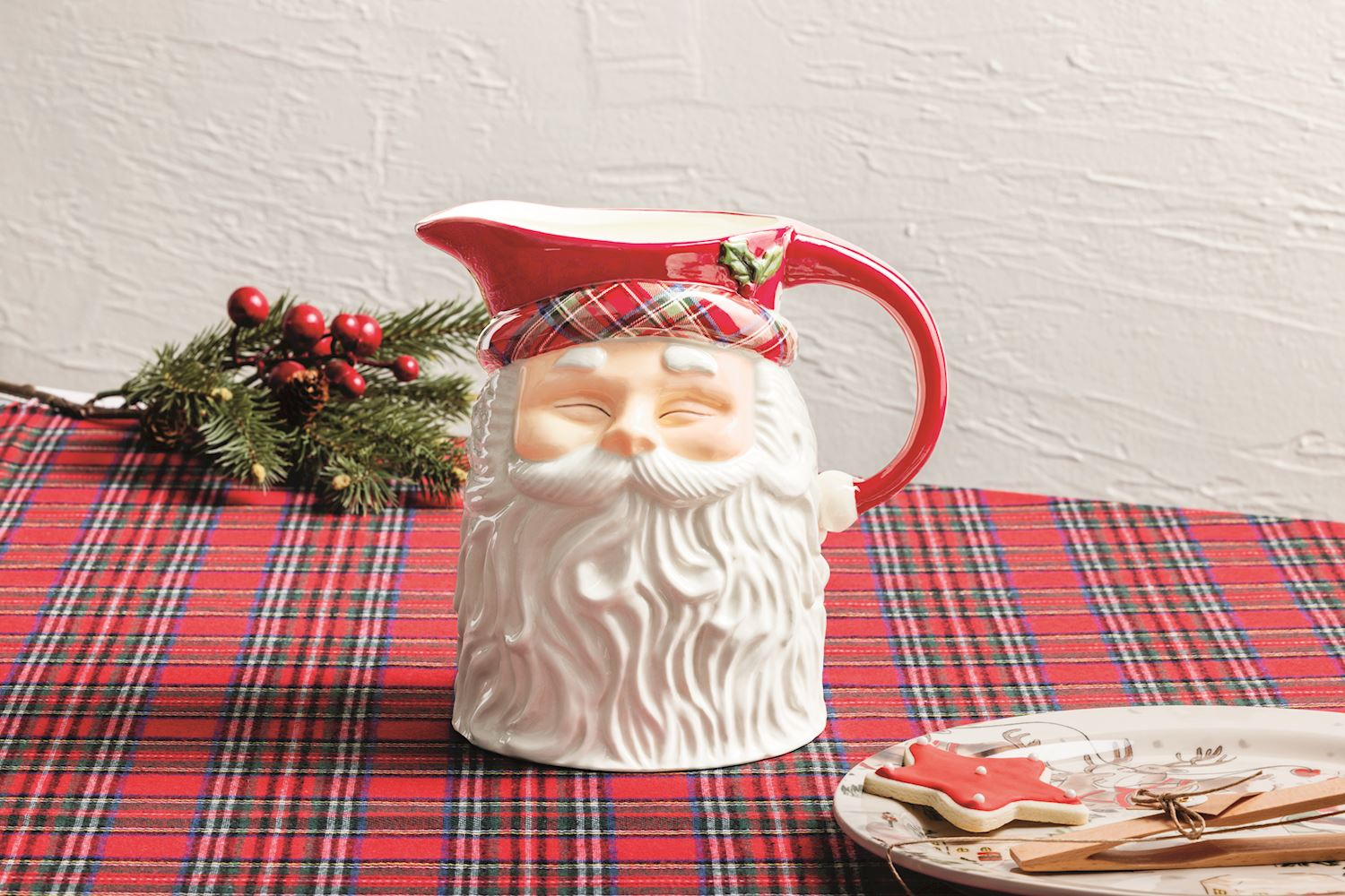 Ceramic Santa Claus pitcher with a red tartan hat and white beard on a red plaid tablecloth.