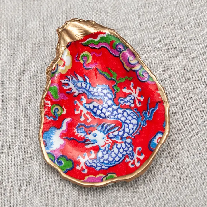 Decoupaged oyster shell with a blue dragon on a red background and metallic gold trim.