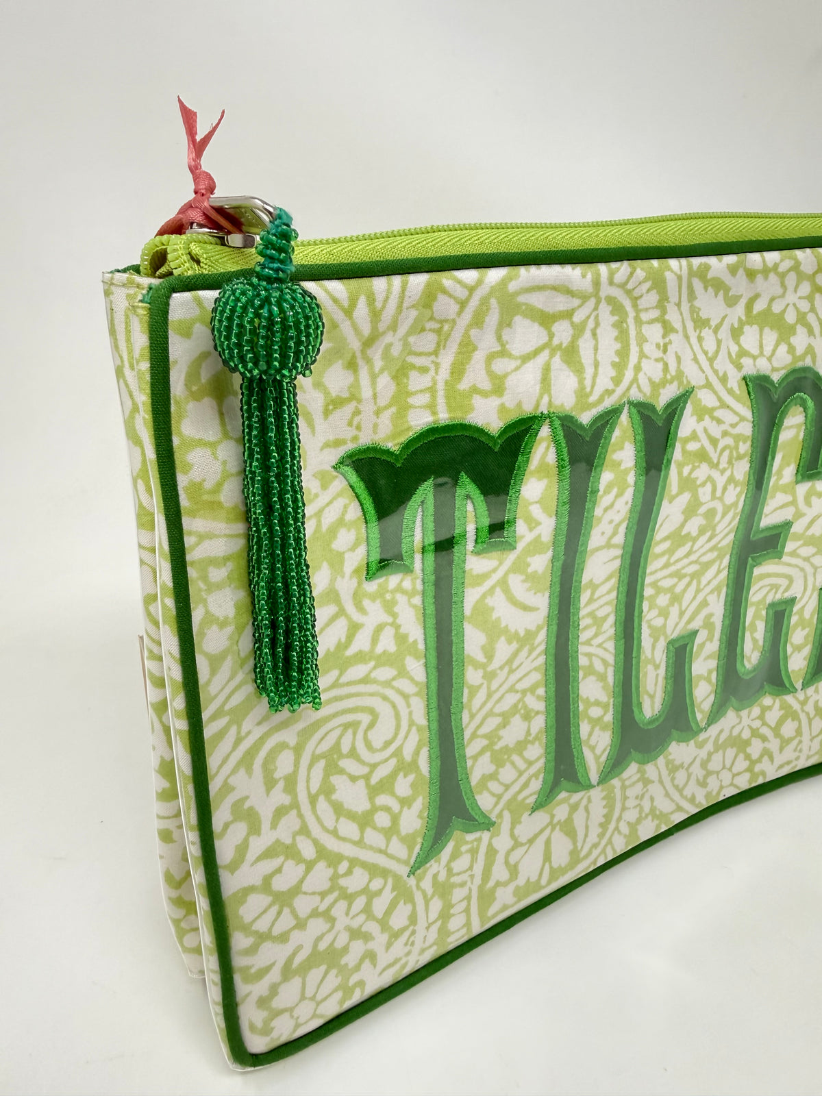Lime green paisley cosmetic bag with a beaded tassel and embroidered 'Tiles' lettering.