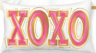 Pink pillow with white pom-pom trim featuring gold foil accents.