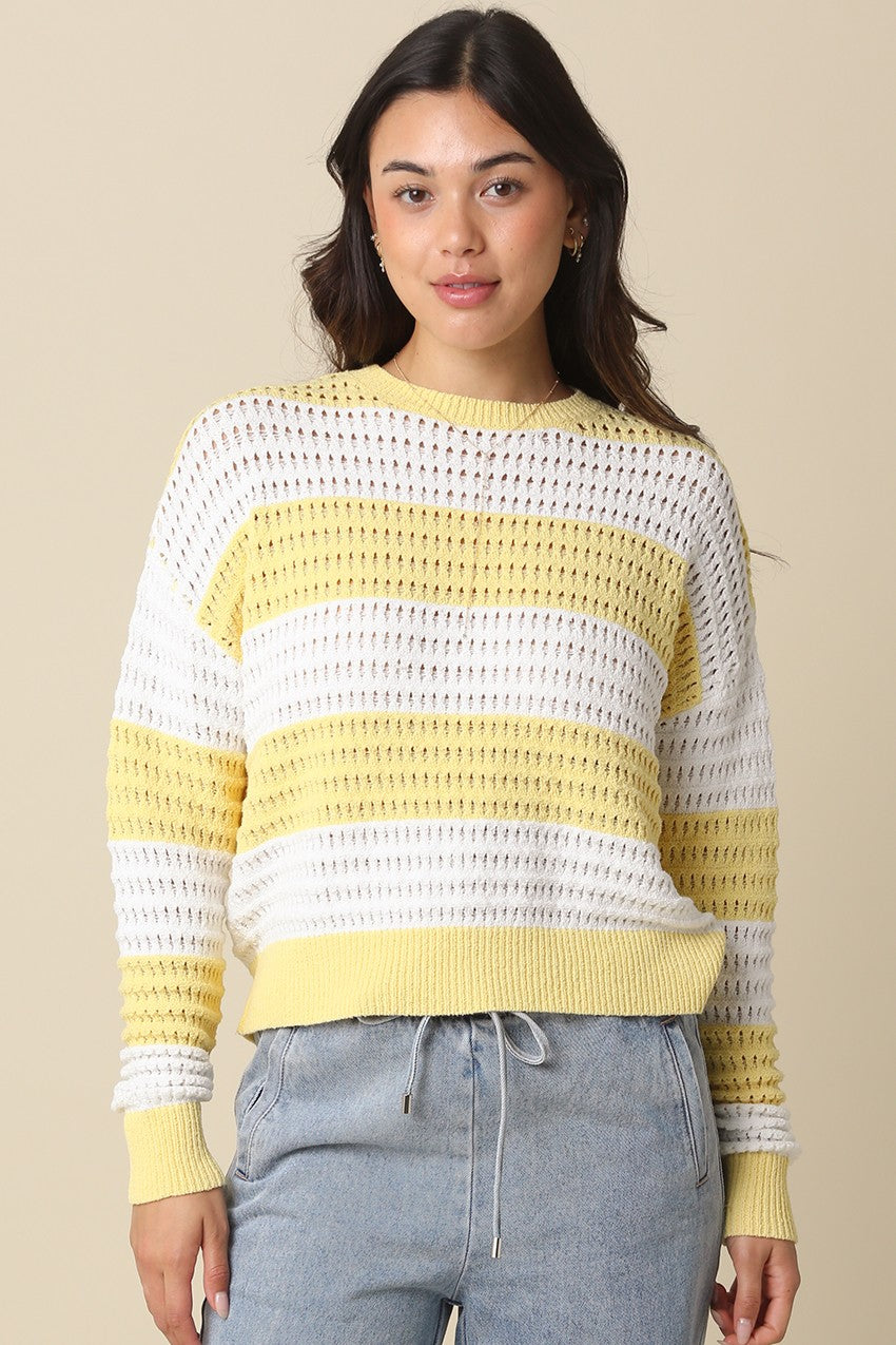 Woman wearing the Sadie Mesh Stripe Knit Sweater in yellow and white with light blue pants.