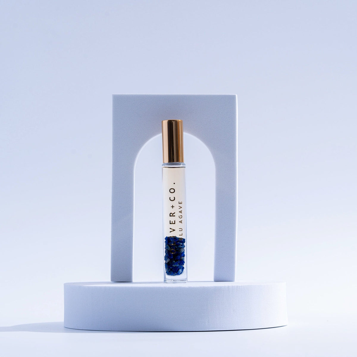 Bougie Stick Blu Agave roll-on perfume with blue crystals inside a glass vial on a white pedestal.