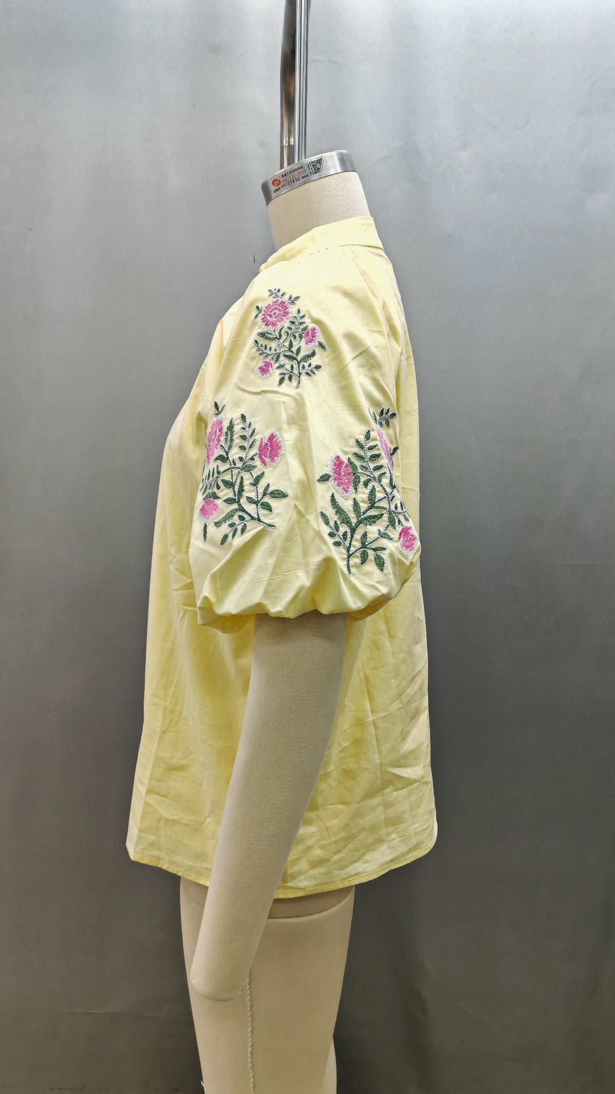 Side view of the Hailey pale yellow top featuring short puff sleeves with pink floral embroidery.