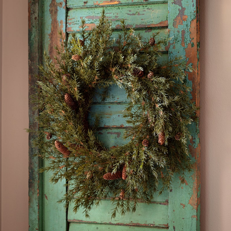 Round wooden wreath with green fir branches and natural rustic texture.