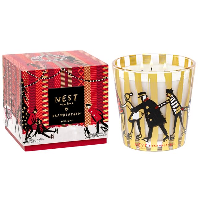 Nest Specialty 3-wick candle in a gold-striped glass jar next to its red holiday-themed box.