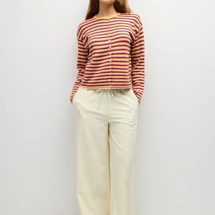 Woman wearing the Cathy Cardigan, a multi-color striped knit with white wide-leg trousers.