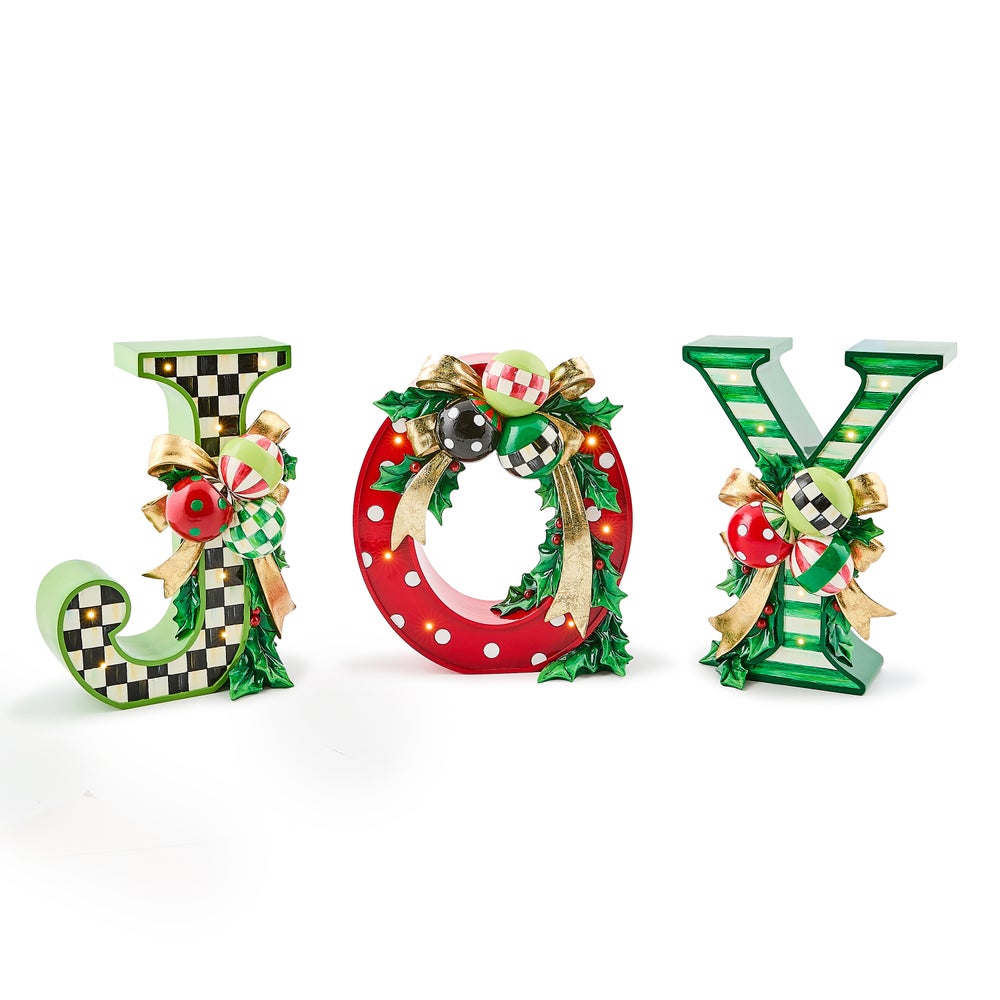 Three illuminated resin letters spelling JOY with checkered, polka dot, and striped patterns.