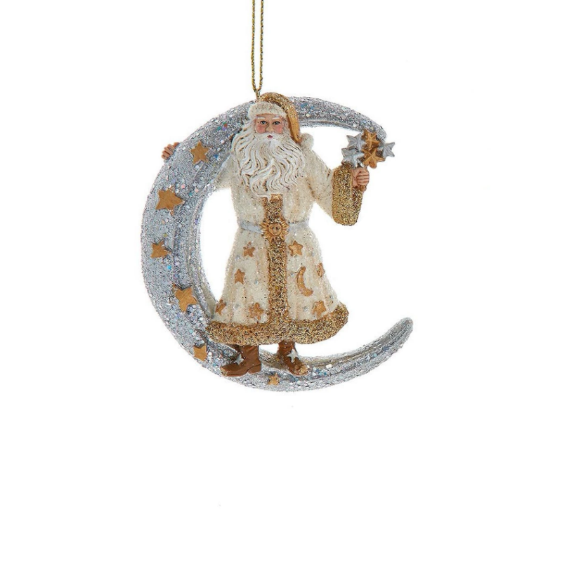 Santa Claus in a white and gold robe standing on a glittery silver crescent moon ornament.