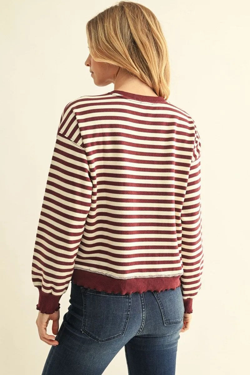 Back view of a woman wearing the Arya burgundy and white striped French terry sweatshirt with jeans.