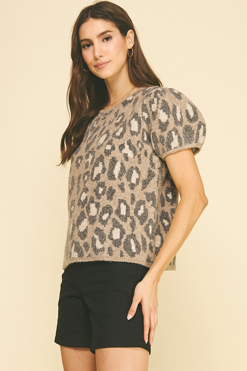 Woman wearing the Maxine leopard animal print knit sweater with short puff sleeves and black shorts.