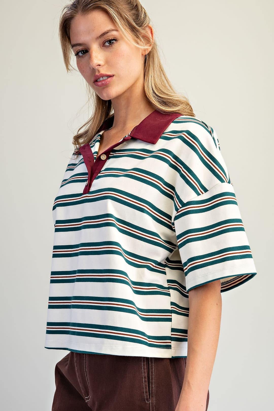 Woman wearing the Cecilia Forest striped oversized polo top with a burgundy contrast collar.