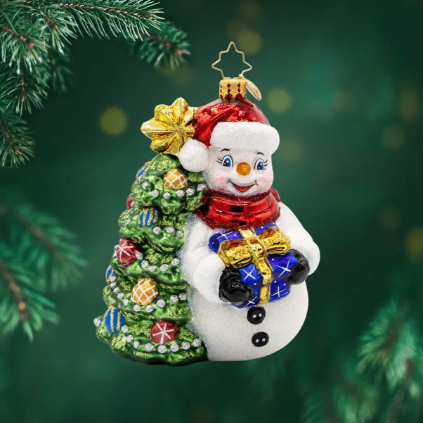 Glass snowman ornament with a Christmas tree and gift, wearing a Santa hat and red scarf.