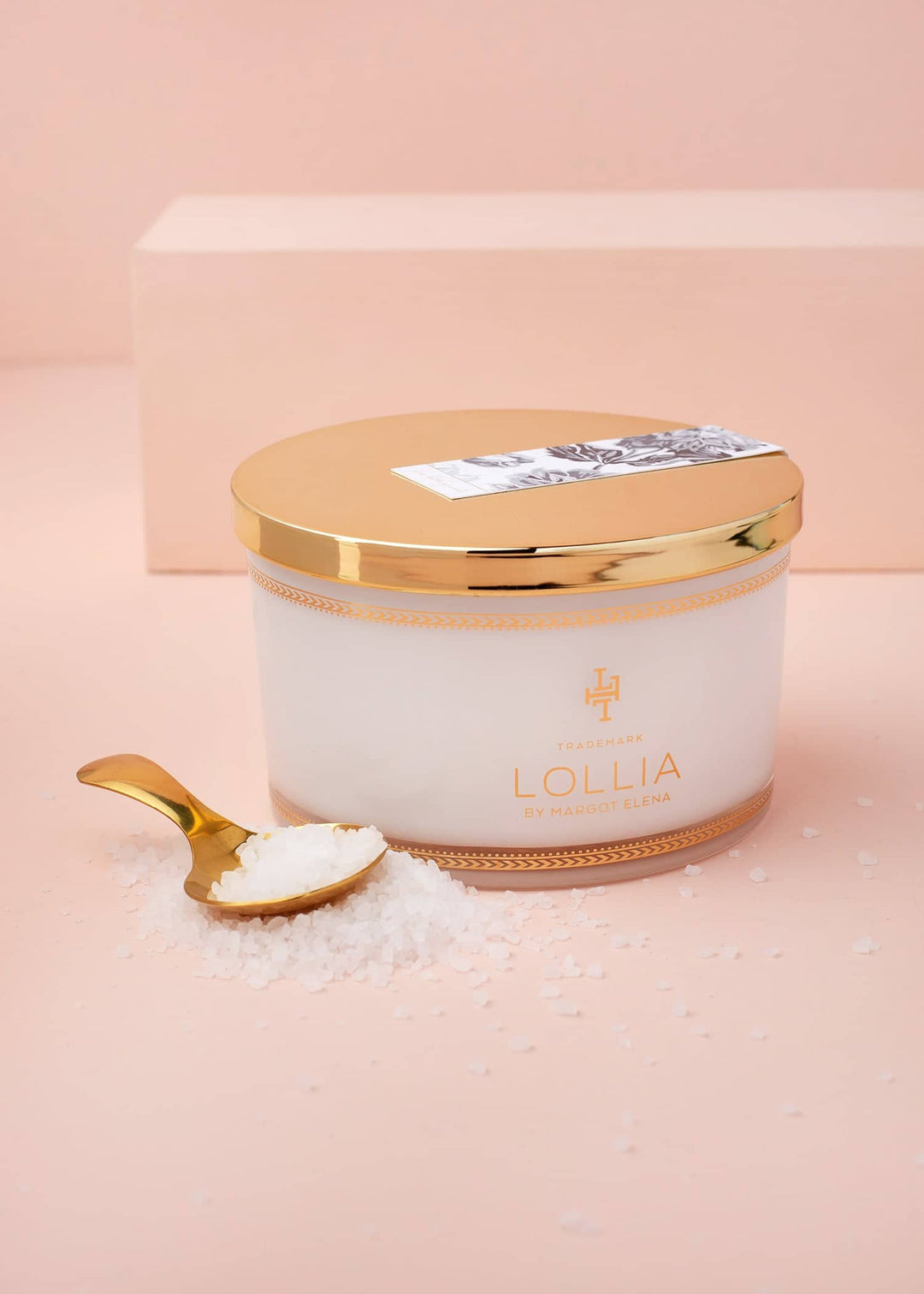 White glass jar with gold accents containing sea salt soak in a linen bag