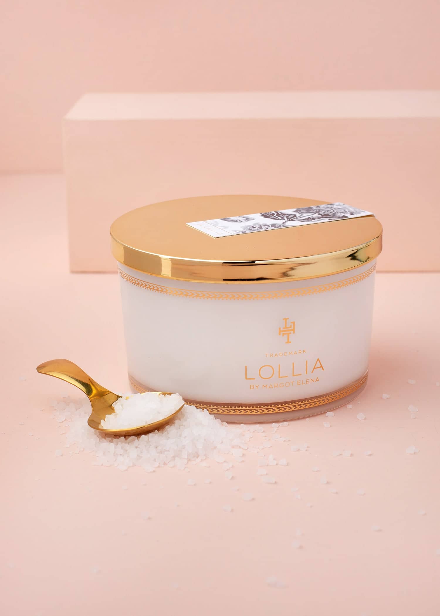 White glass jar with gold accents containing sea salt soak in a linen bag