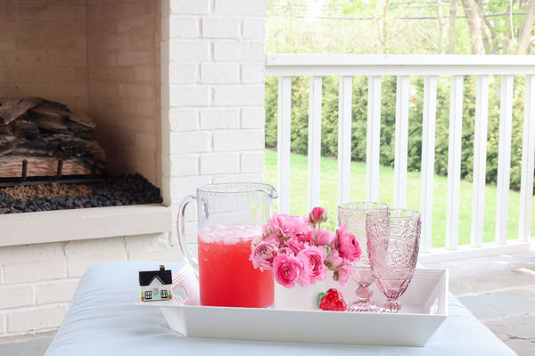 White Pinstripes Melamine Tray holding a pitcher of pink drink, flowers, and two glasses on a patio.