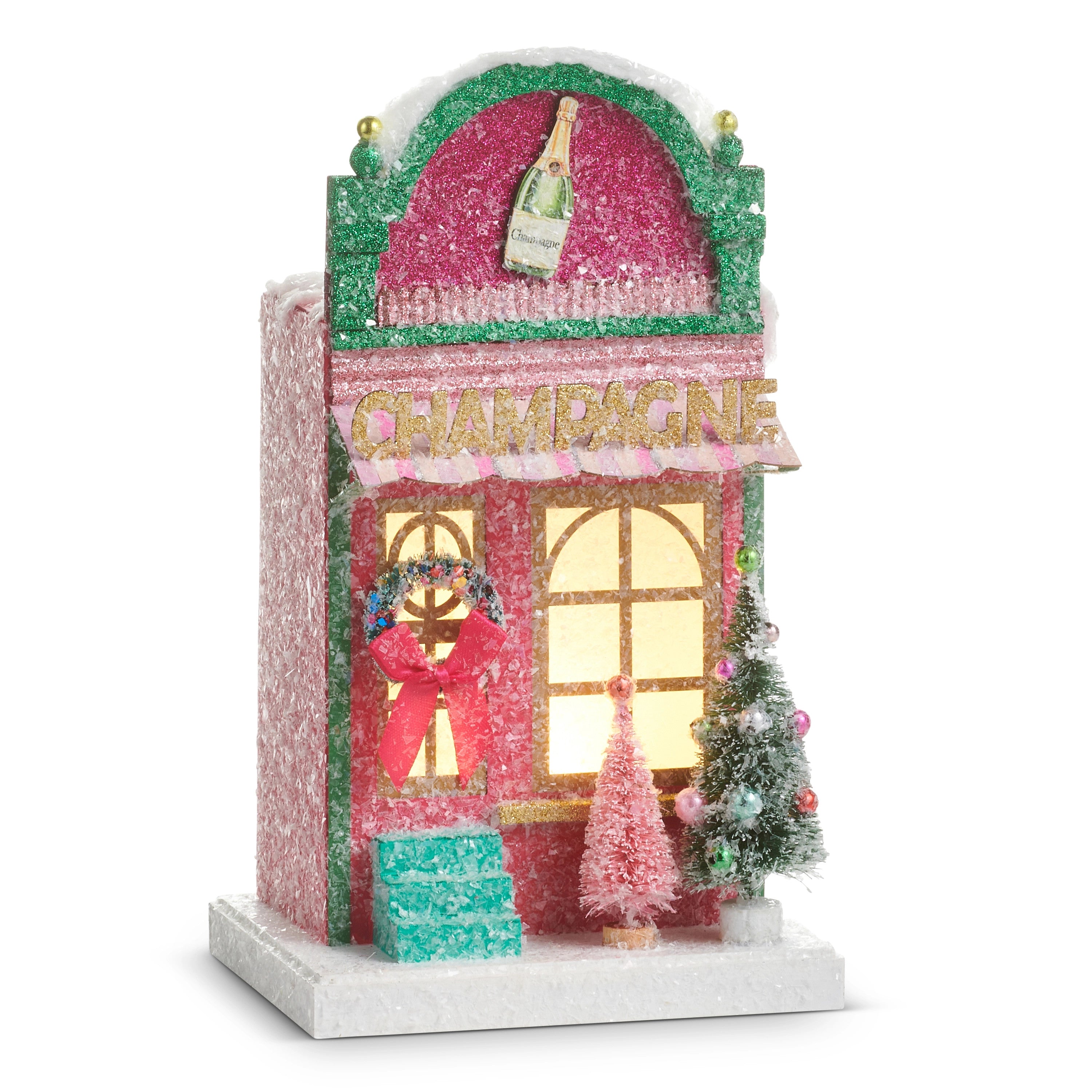 Lighted pink glitter champagne lounge paper house with a wreath, bottle sign, and Christmas trees.