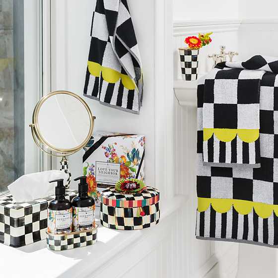 Hand-painted black and white checkered enamel tissue box cover on a bathroom counter.
