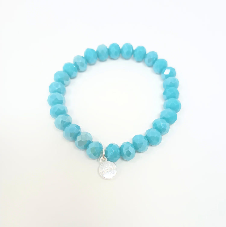 Stretchy beaded bracelet with faceted turquoise glass beads and a small silver charm.