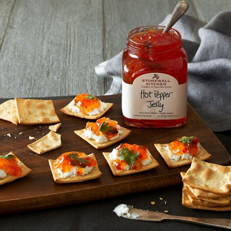 Glass jar containing red hot pepper jelly with visible onion pieces.