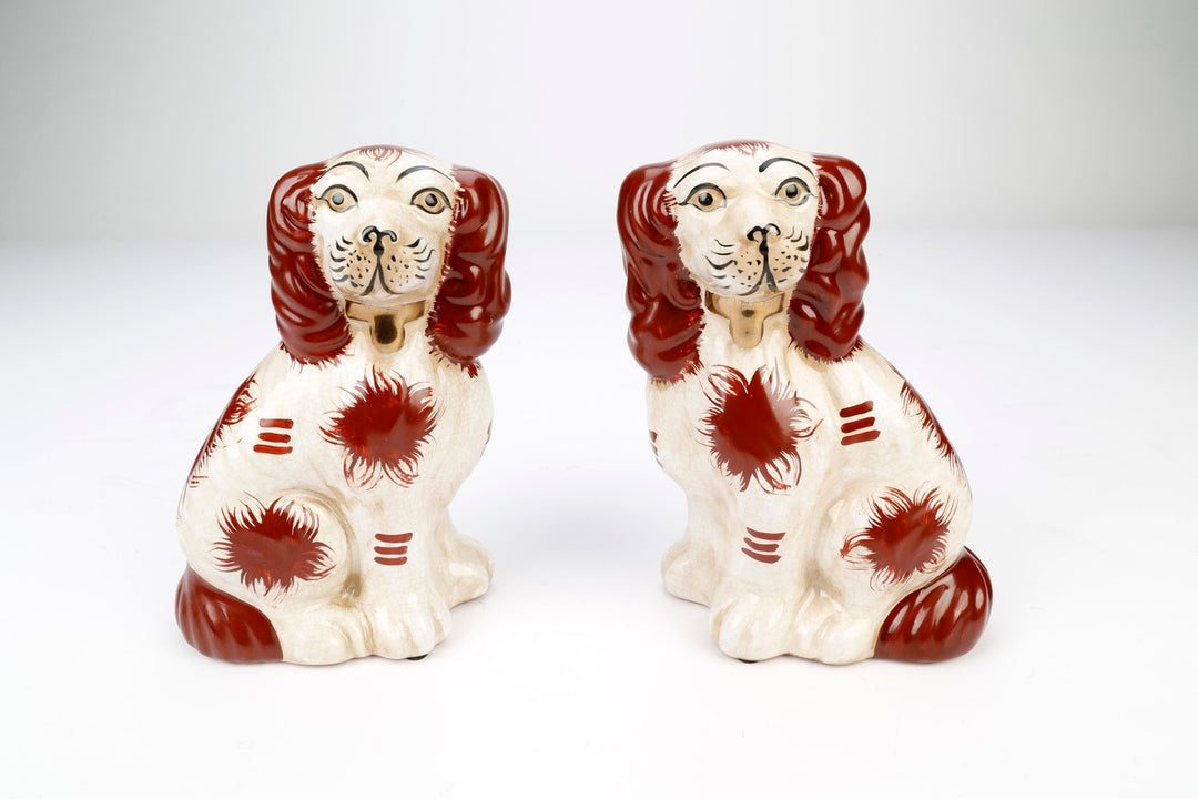 Set of two Staffordshire spaniel dog figurines in black glazed ceramic with white accents.