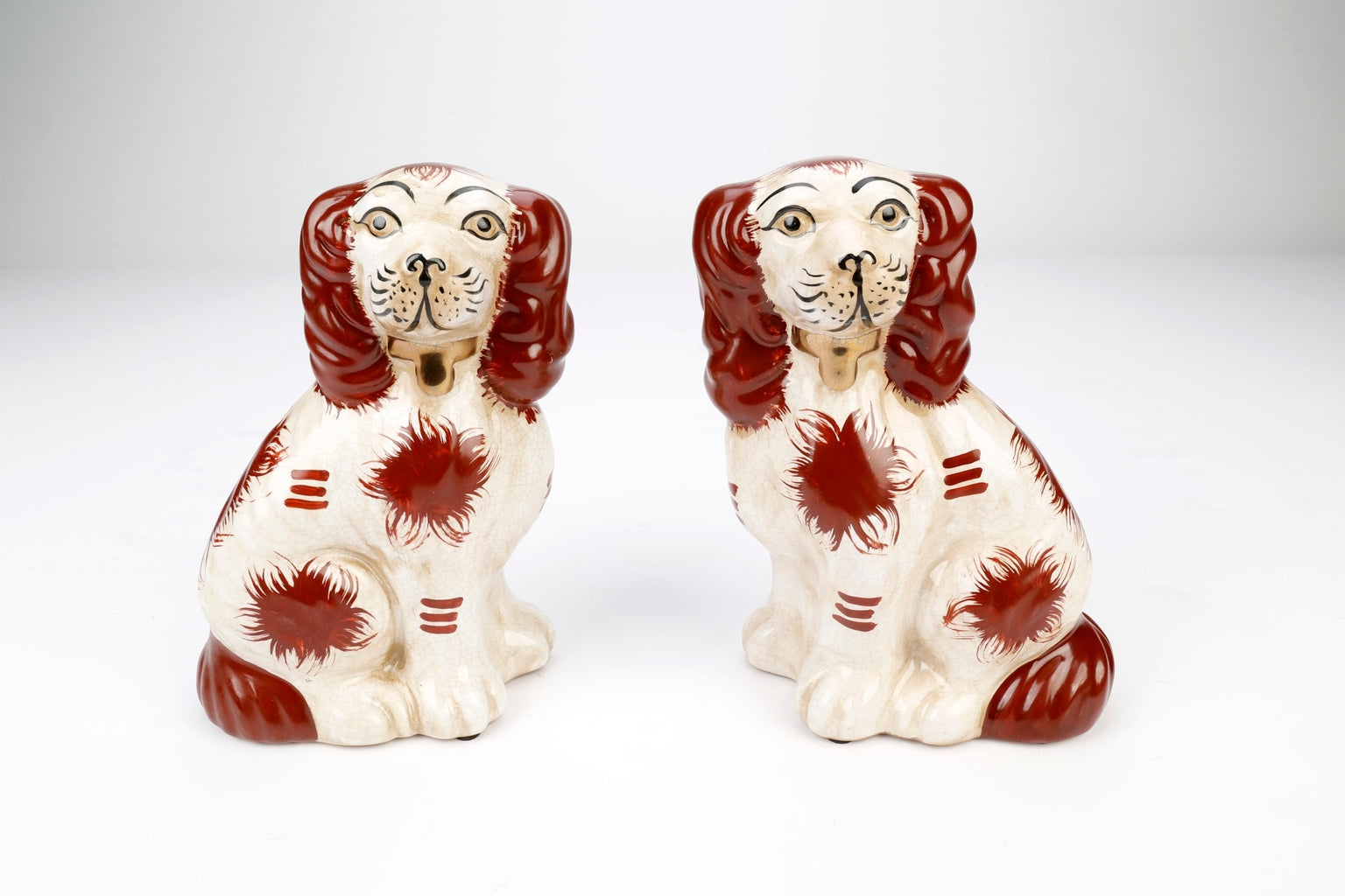 Set of two Staffordshire spaniel dog figurines in black glazed ceramic with white accents.