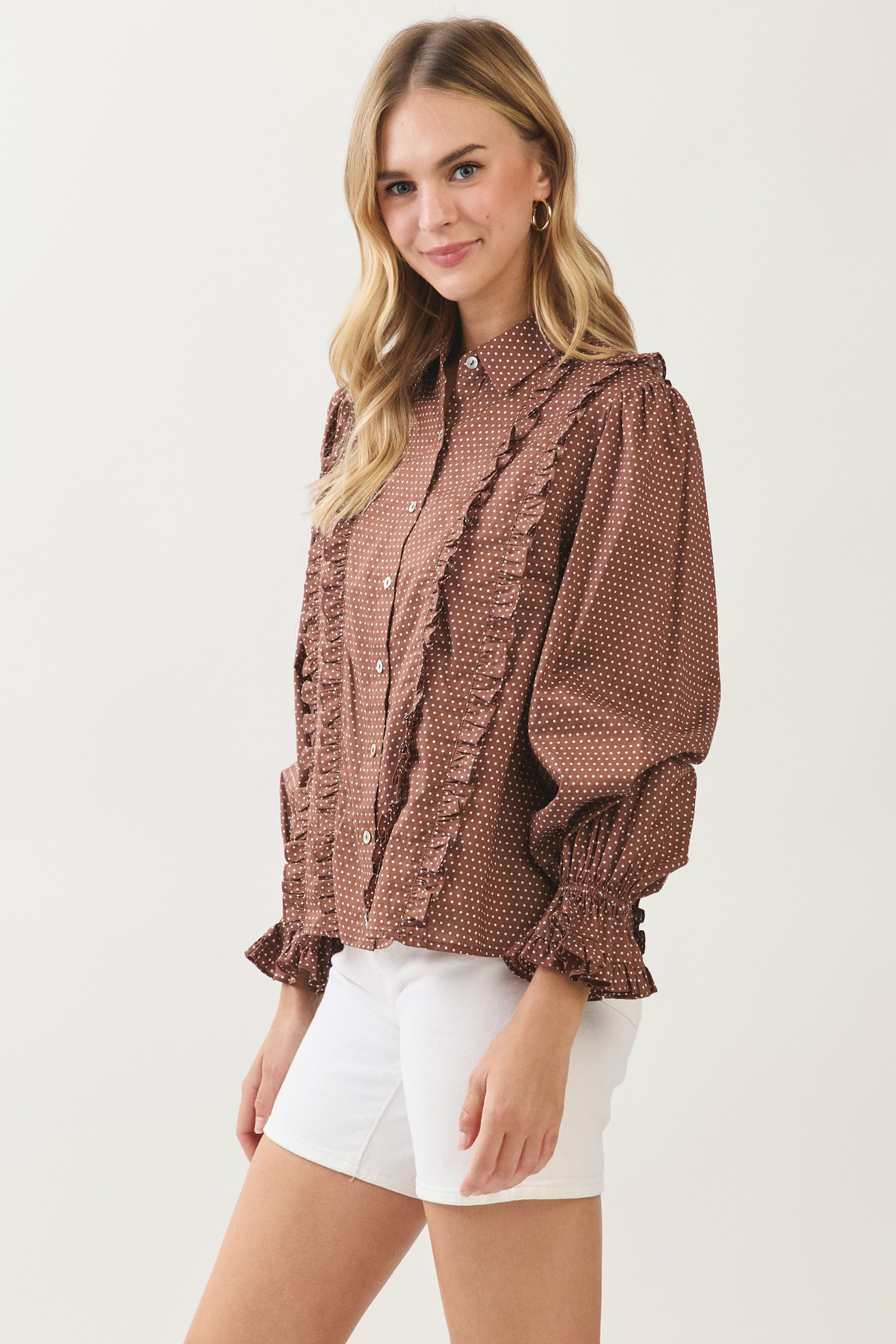 Woman wearing the Willa Polka Dot Button Down Shirt in brown with white dots and ruffled details.