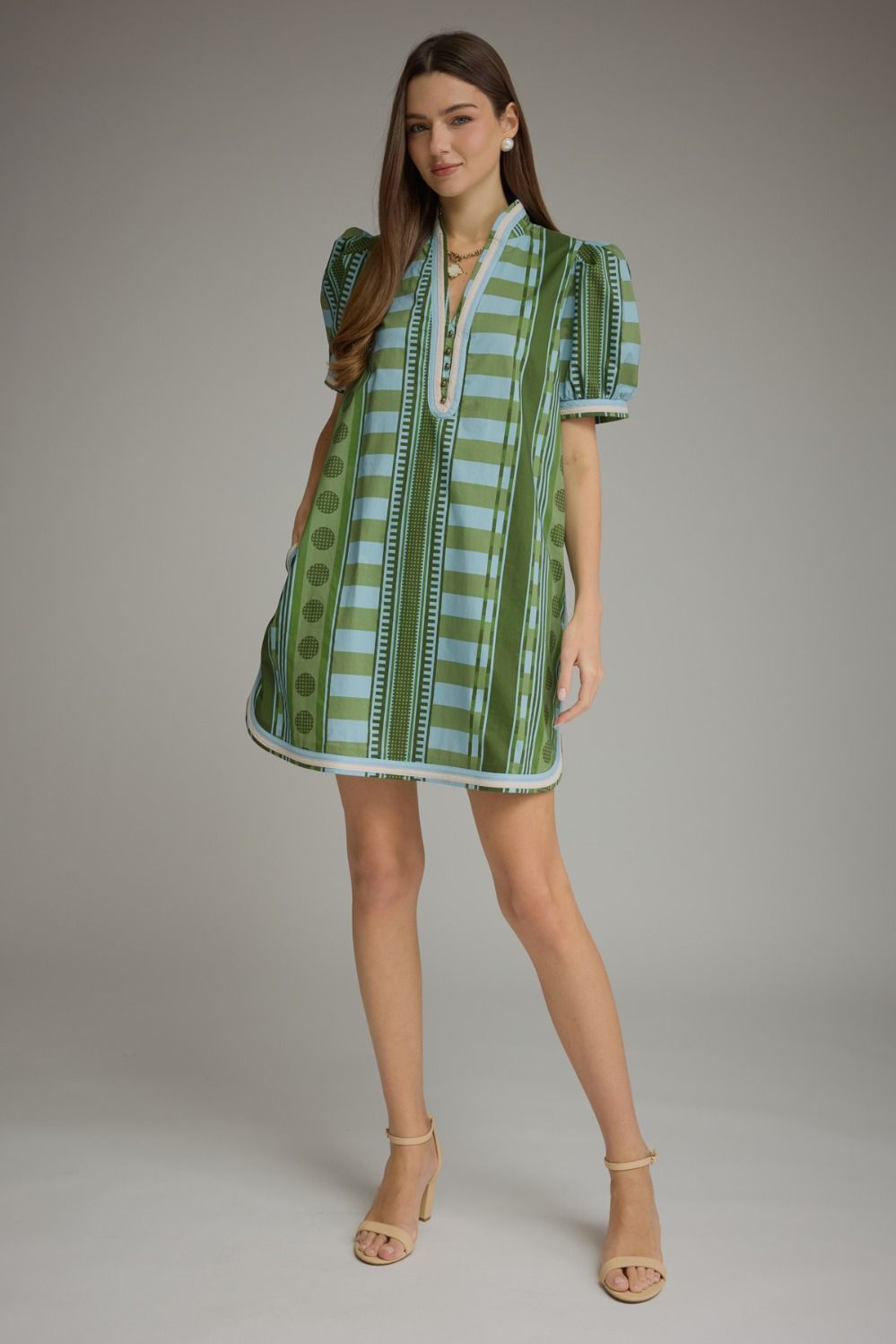 Woman wearing a Gabrielle green and blue striped mini dress with puff sleeves and V-neck detail.