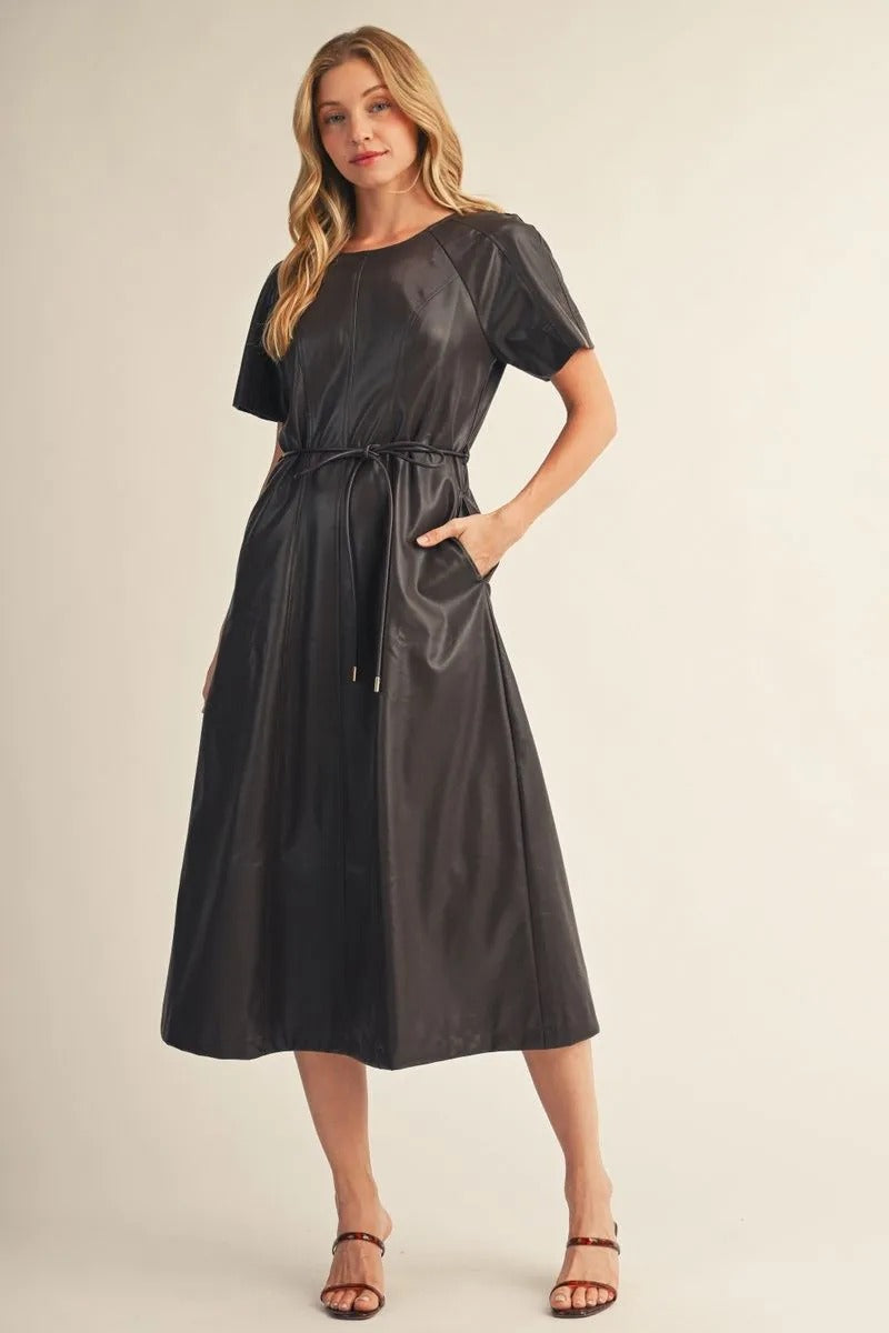 Woman wearing the Allison Short Sleeves Faux Leather Midi Dress in black with a tie waist.