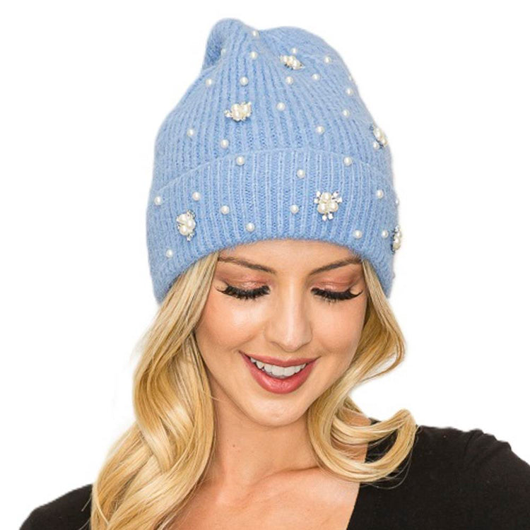 Black knit beanie with a fluffy pom-pom top and small pearl studs along the brim.