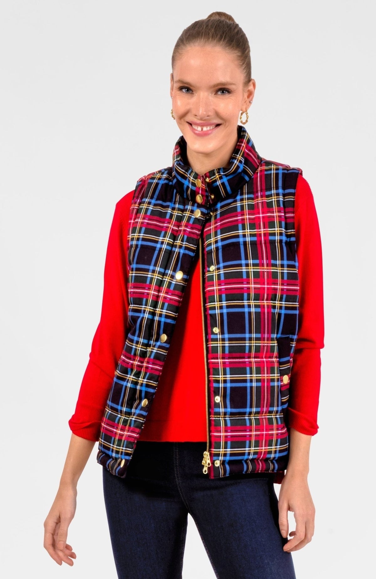 Woman wearing a Stewart Plaid puffer vest with gold snaps and zipper over a red long-sleeve top.