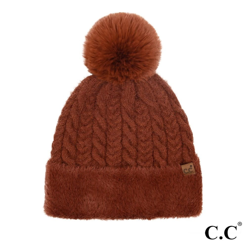 Brick-colored cable knit beanie with faux fur cuff and pom top