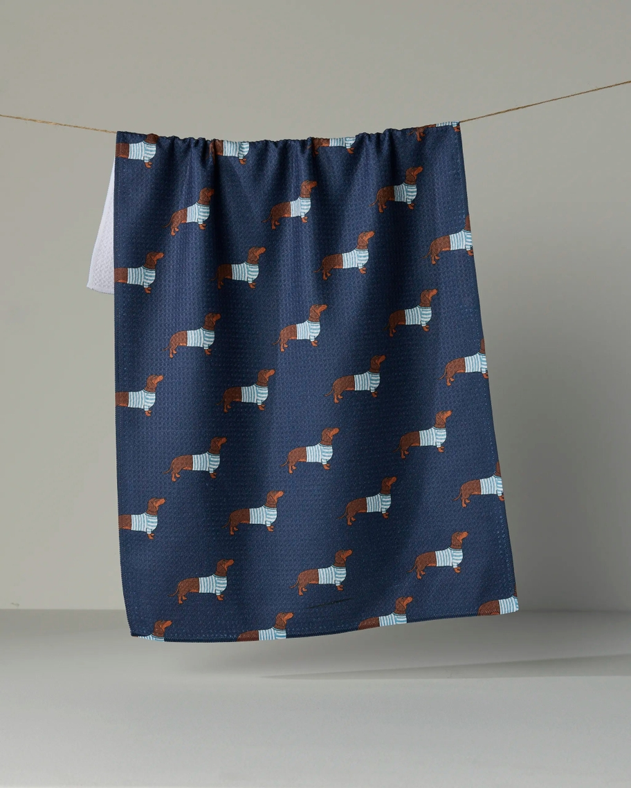 Navy blue waffle-knit tea towel with a pattern of brown dachshunds wearing blue striped sweaters.