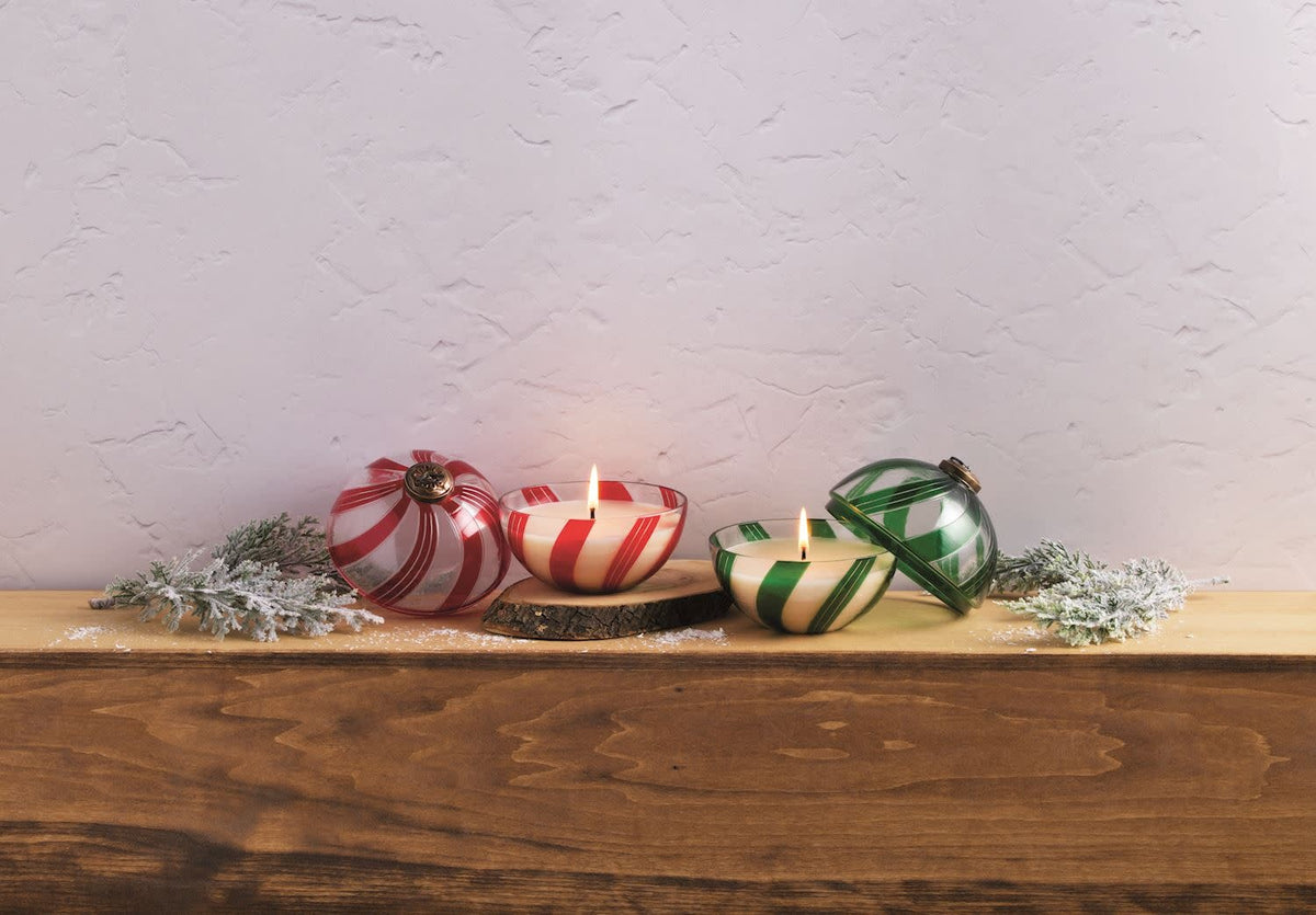 Glass ornament candle with lid in candy cane red and white stripes, smoked cedar scent.