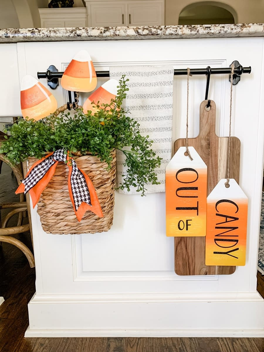 Three candy corn shaped plastic yard stakes in orange, yellow, and white arranged vertically.