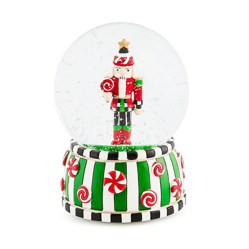 Resin snow globe featuring a candy-themed nutcracker soldier with red hat inside glass sphere.