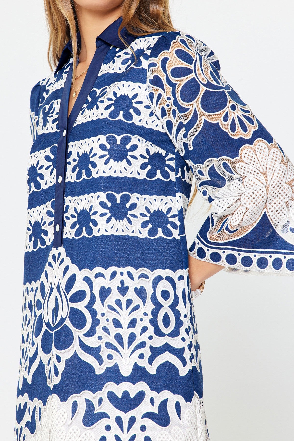 Mini dress with collared neckline, button placket, lace embroidery, floral pattern, and side pockets.