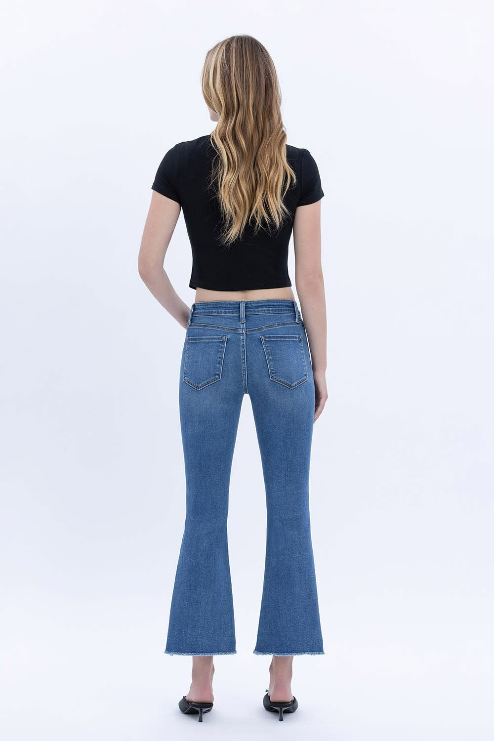 Back view of mid-rise crop flare jeans with raw step hem in stretch denim.